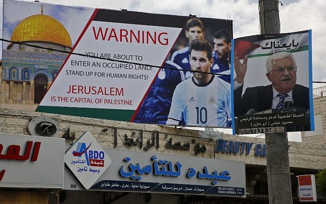 A poster erected in the West Bank calling for a boycott of soccer star Lionel Messi next to a portrait of the Palestinian Authority President Mahmoud Abbas. Photo: AFP/ HAZEM BADER